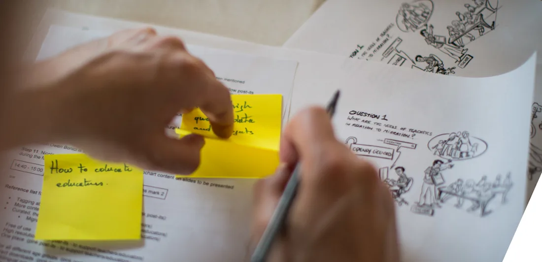 Hands writing on sticky notes