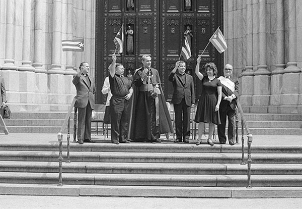 group of people holding flags on steps outside cathedral