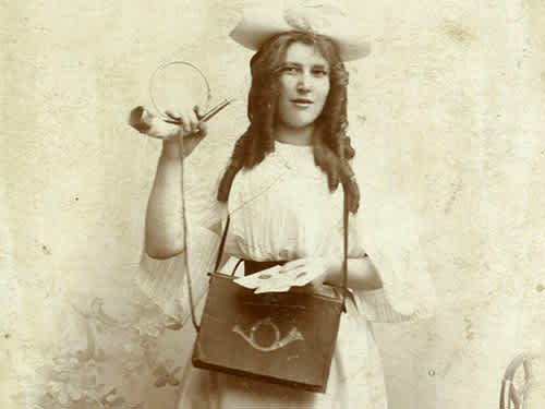 černobílá fotografie mladé ženy držící hudební nástroj podobný rohovi a tašku s obrázkem lesního rohu