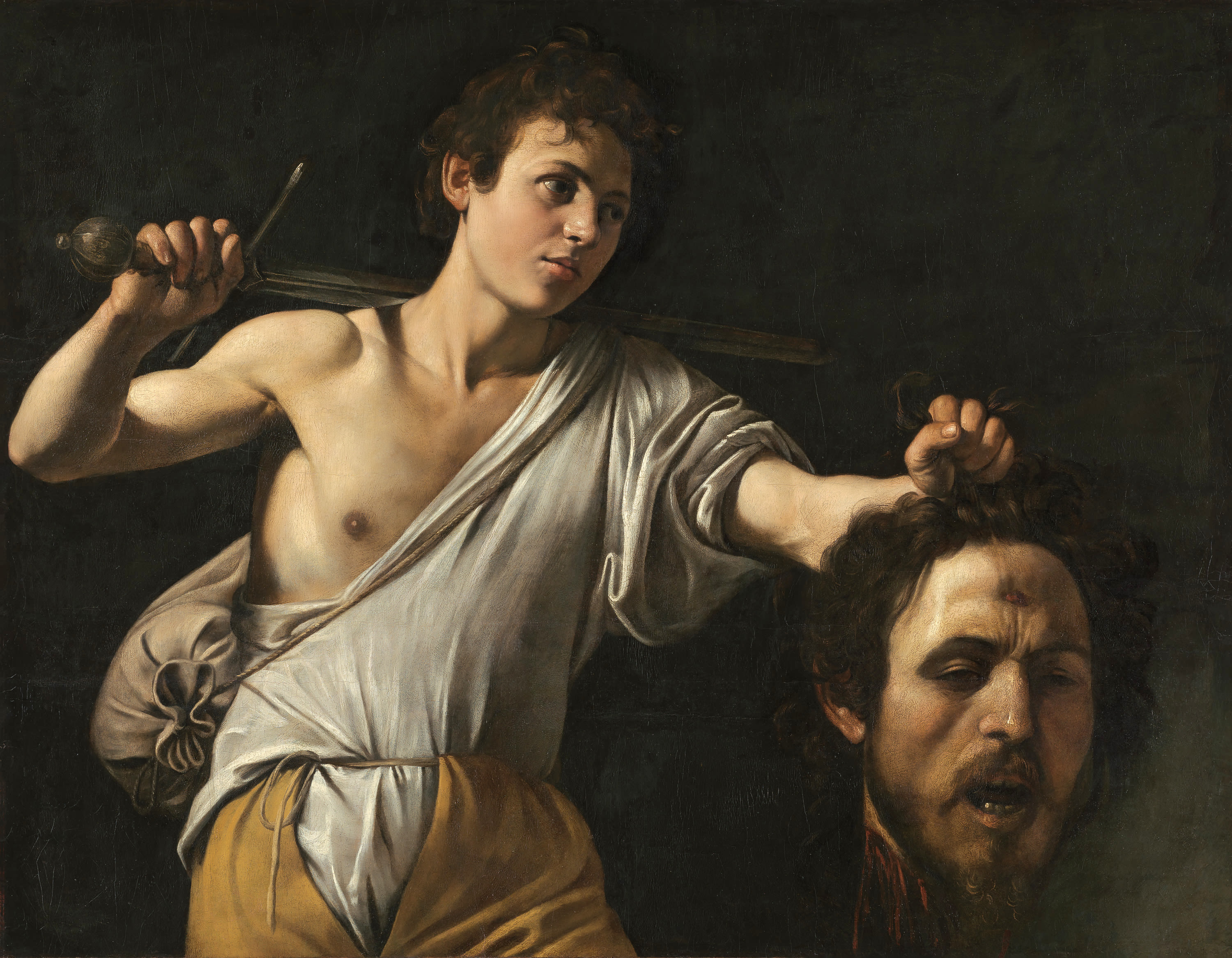 painting, a young man holds the head of another man in one hand and a sword in the other, behind his back.