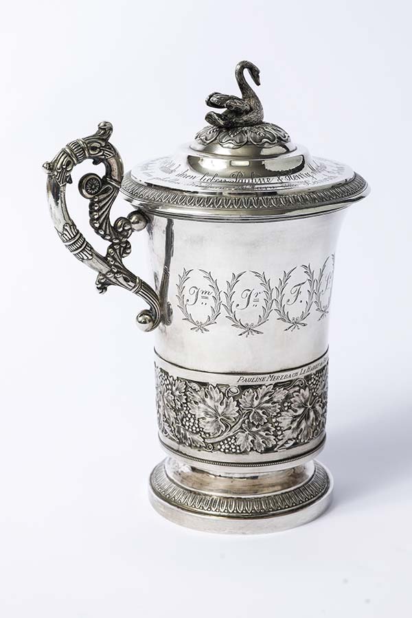 large silver cup with engravings and decorative lid
