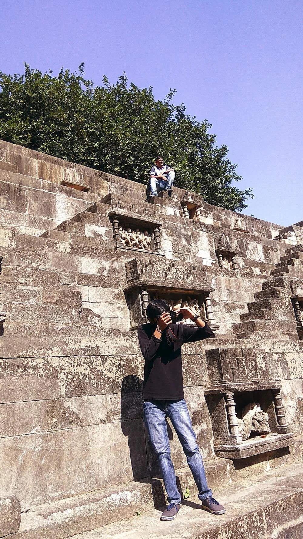 A person taking a photograph at a historic stepped reservoir in Gujarat, India
