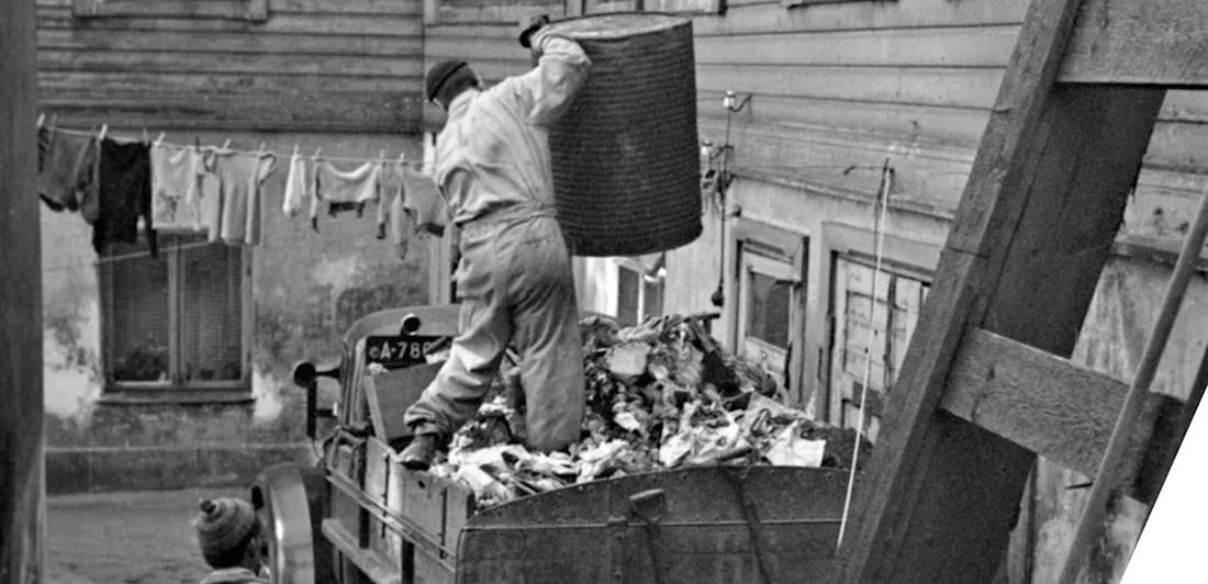 A refuse collector stood on a cart