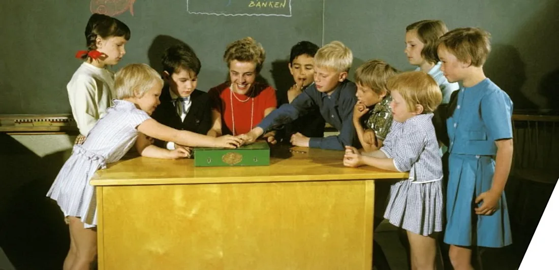 A group of children crowded round a desk in a classroom