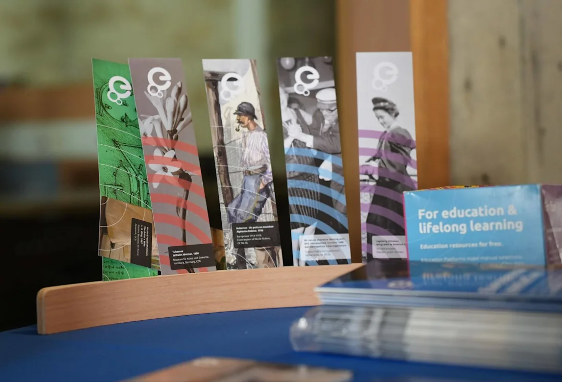 Colorful educational brochures in a wooden holder on a table, with more pamphlets stacked nearby.