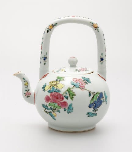 a white glazed teapot with colourful flower decorations