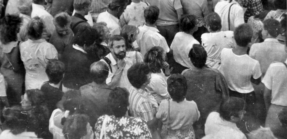 black and white photograph, a man standing among a crowd of people.