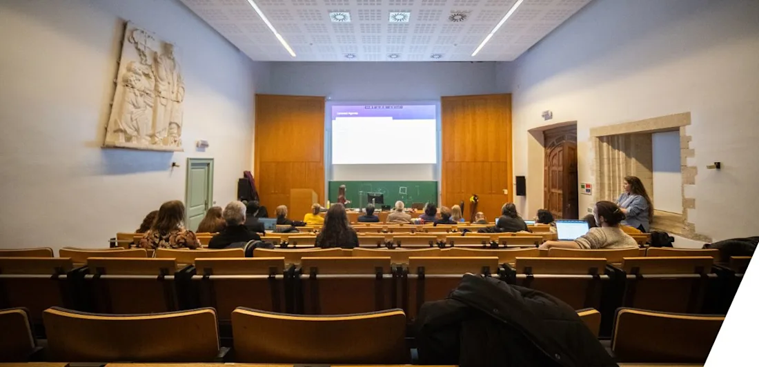 A lecture theatre with attendees seated looking at a screen