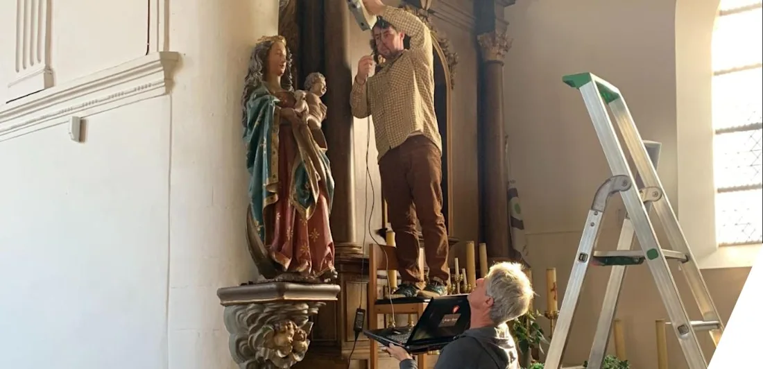 Two men scanning a mounted statue of the Madonna and child