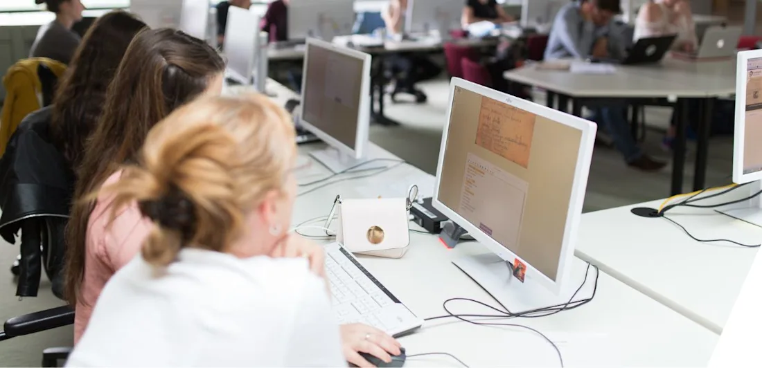 Two women looking at a manuscript on a computer.