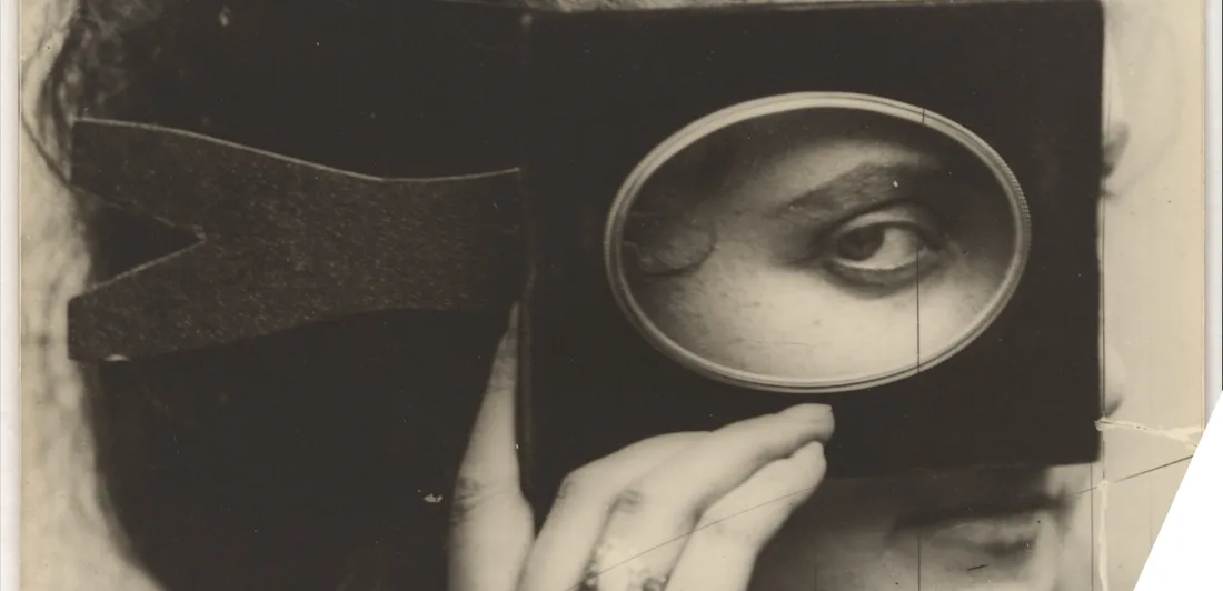 A woman peering through a black piece of cardboard