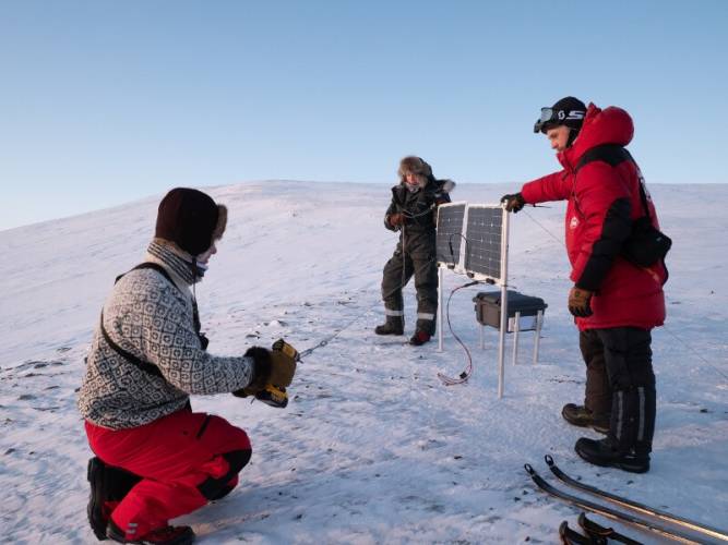 Researchers set up a camera and solar panels near a polar bear den site