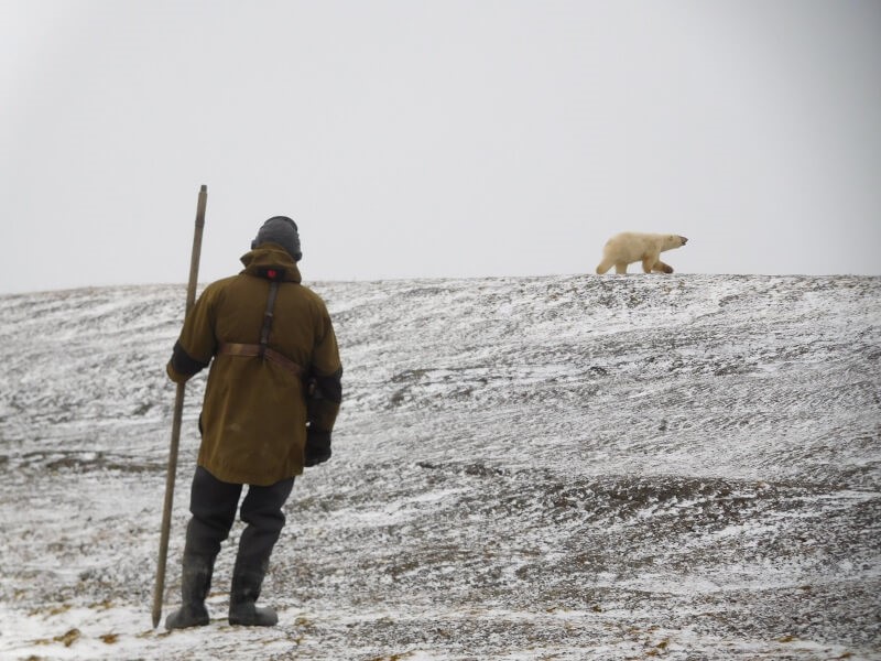 A Russian researcher keeps an eye on a nearby polar bear