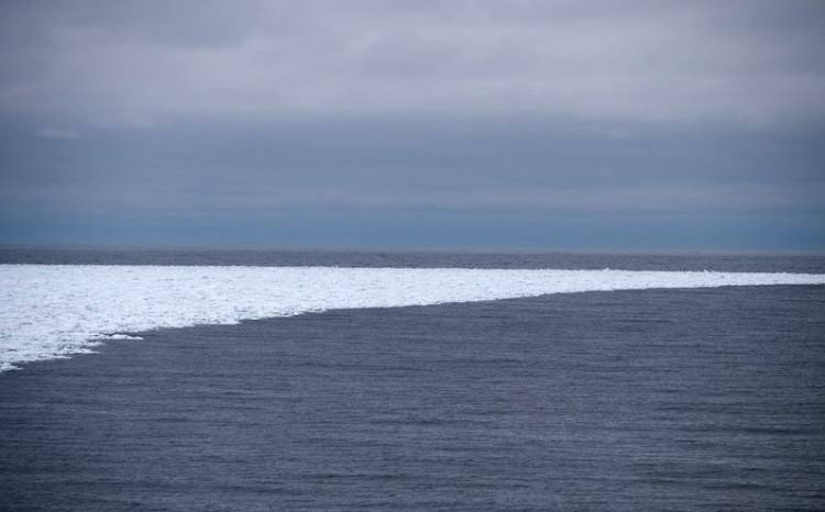 A small band of sea ice curves into open ocean waters.