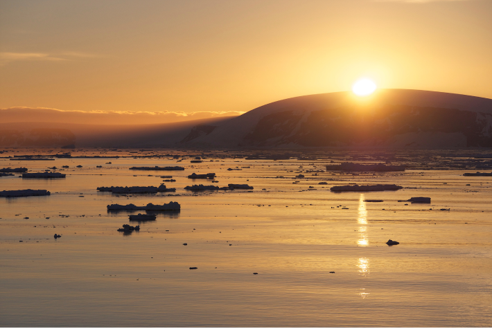 The sun peeking behind a glacier