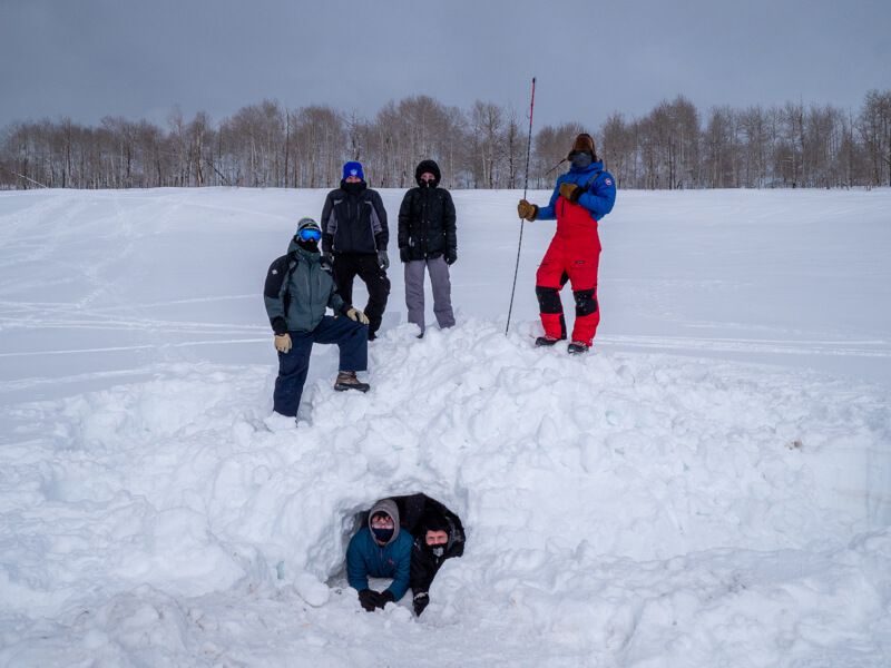 Researchers pose by an artificial den constructed for test purposes in Utah
