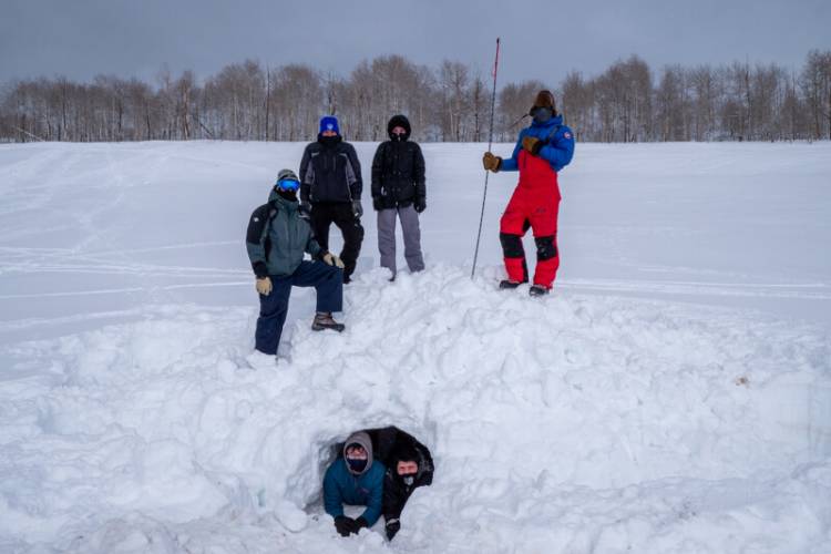 Researchers pose by an artificial den constructed for test purposes in Utah