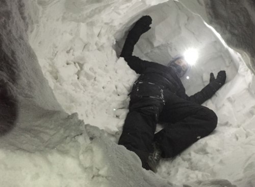 Wes Larson crawls inside an artificial snow den to see if the SAR device can detect him while flying overhead