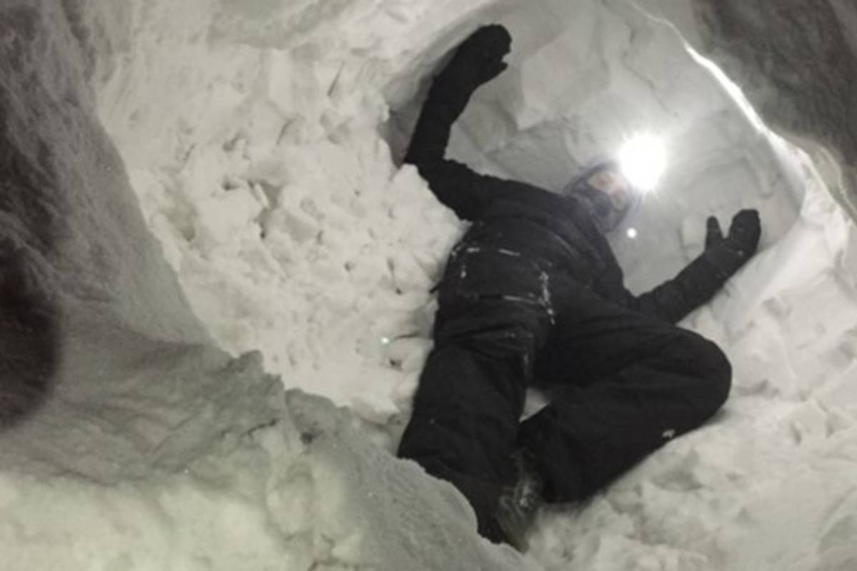 Wes Larson crawls inside an artificial snow den to see if the SAR device can detect him while flying overhead