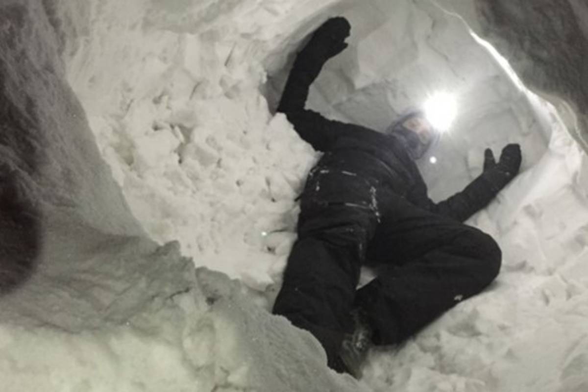 Wes Larson crawls inside an artificial snow den to see if the SAR device can detect him while flying overhead