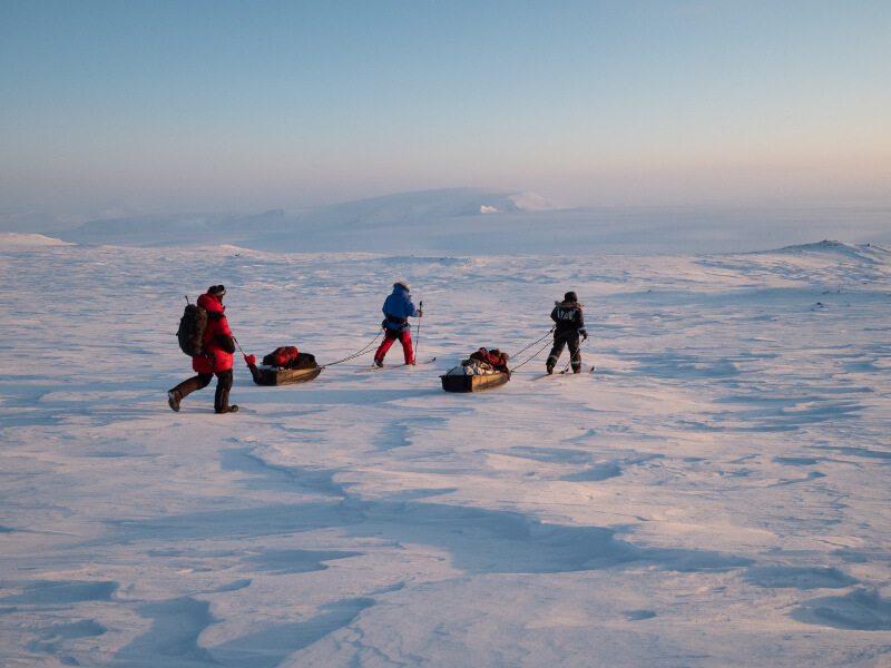Researchers pull sleds with camera gear and other equipment to a polar bear den site