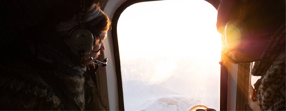 Researchers looking out the window at a vast Arctic landscape