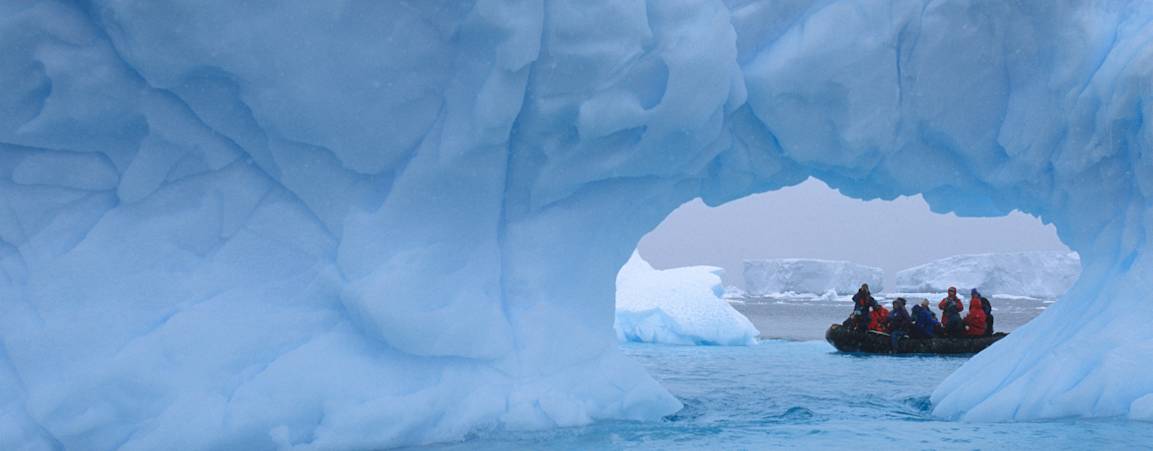 Team of researchers inside a small boat in the arctic, surrounded by ice caps