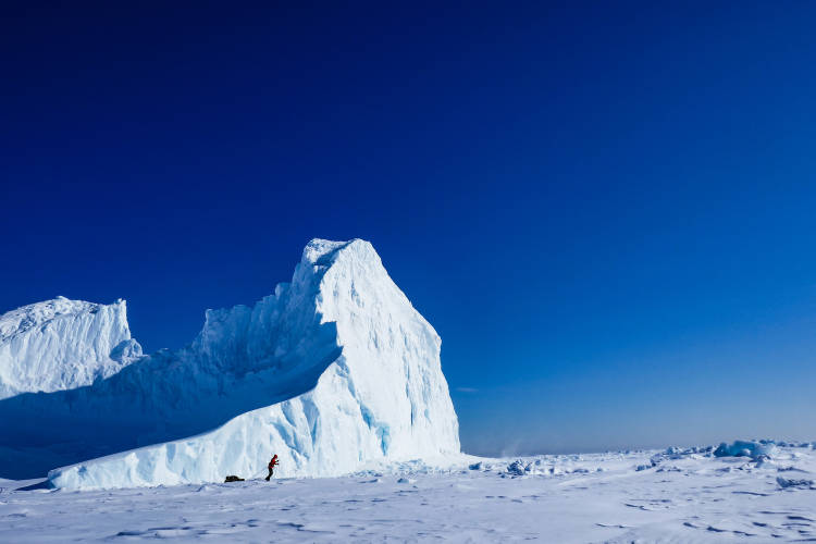 Frank Wolf skis by a behemoth iceberg that had calved off from a glacier in Greenland