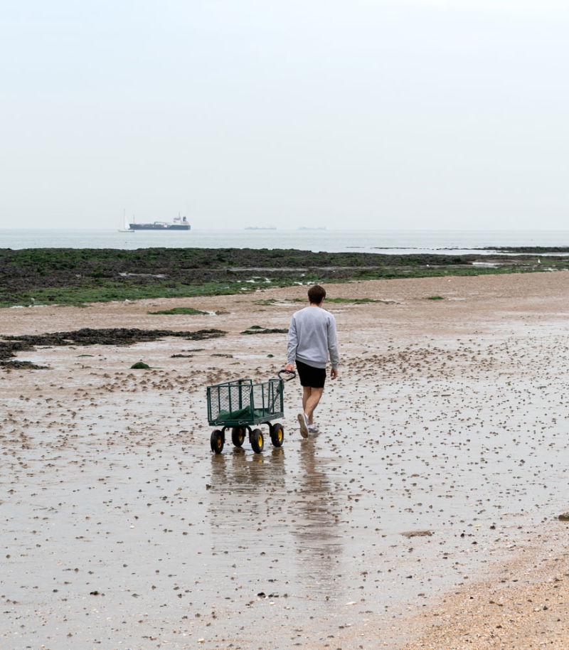 Man walking on the beach with seaweed 