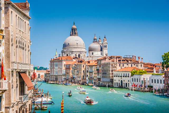 Small boats on the Canal Grande, with Basilica di Santa Maria della Salute in the background on a sunny day, Venice, Italy