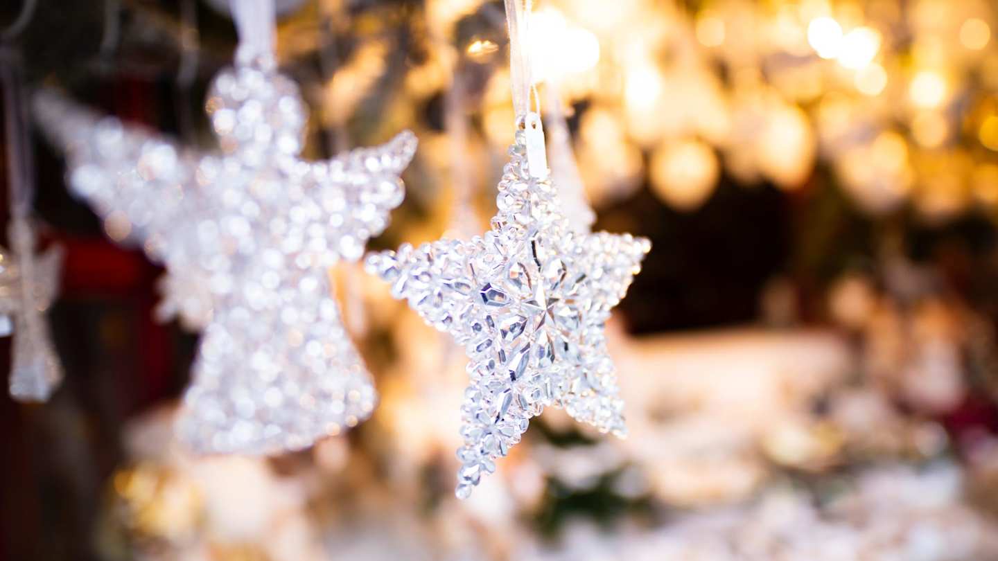 A star ornament and an angel ornament hanging on a Christmas tree