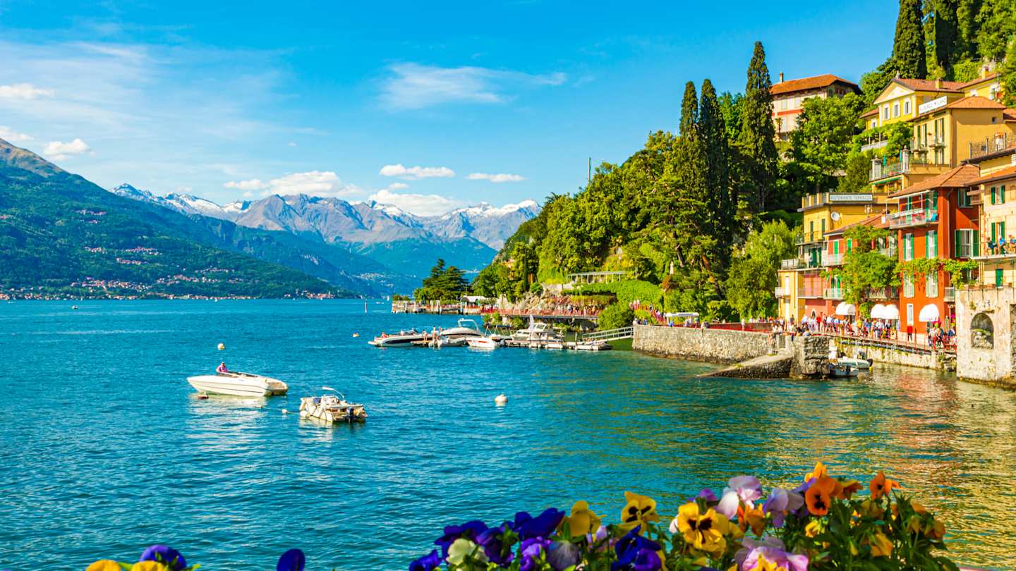 The waterfront village of Varenna, with mountains in the background and boats on the lake, Lake Como