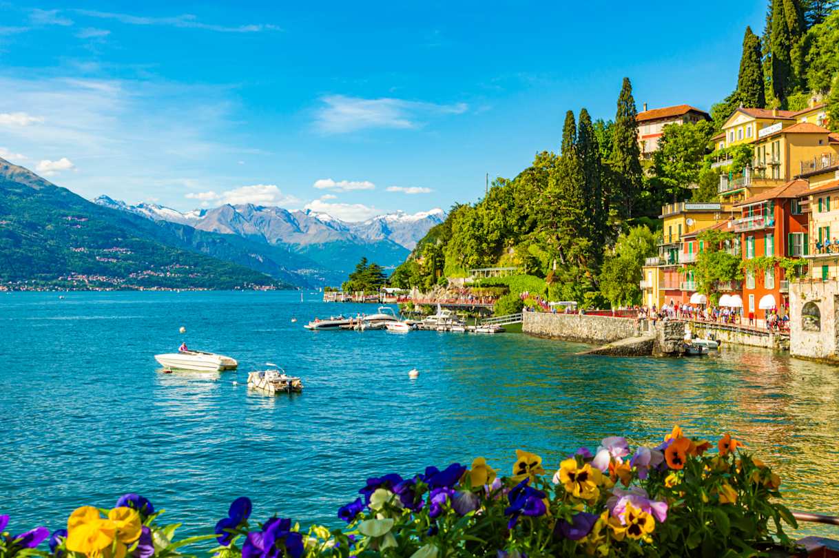 The waterfront village of Varenna, with mountains in the background and boats on the lake, Lake Como