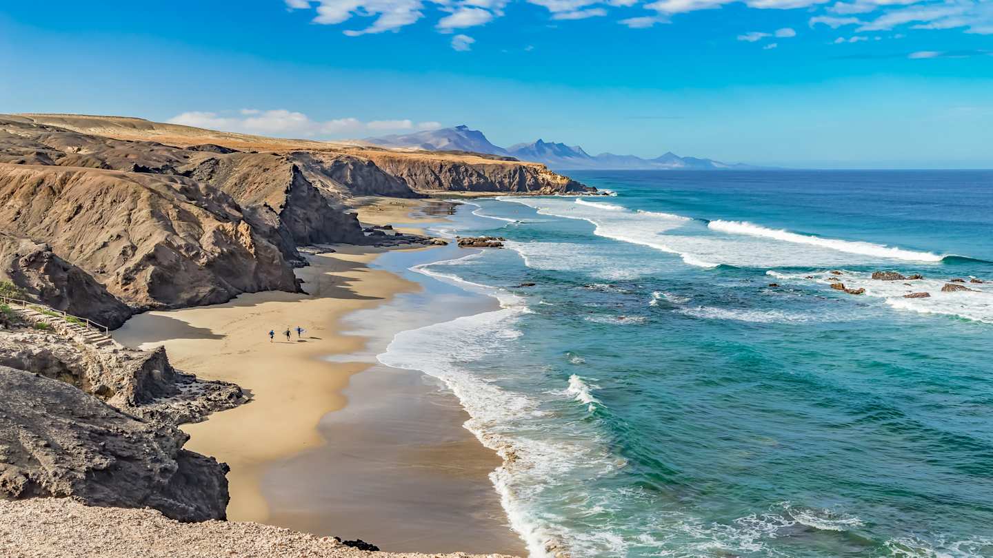 Rocky coastline with Atlantic waves crashing on the sandy beach, Fuerteventura