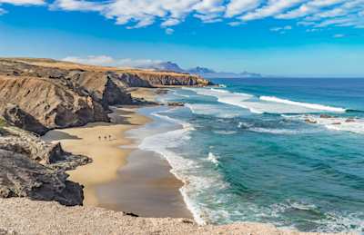 Rocky coastline with Atlantic waves crashing on the sandy beach, Fuerteventura