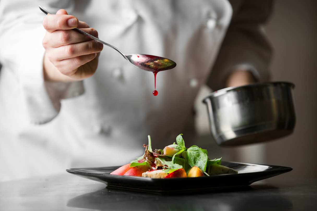 A close up view of a chef drizzling red sauce over a neat dish at a London restaurant
