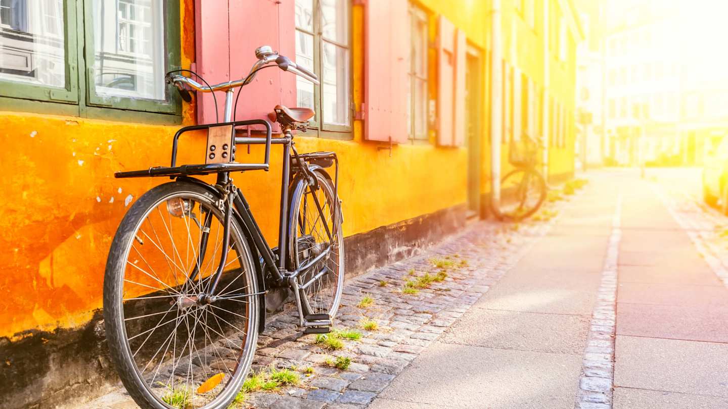 A bicycle leaning against an orange wall at sunset in Copenhagen, Denmark