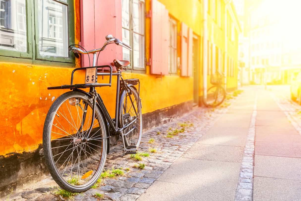 A bicycle leaning against an orange wall at sunset in Copenhagen, Denmark