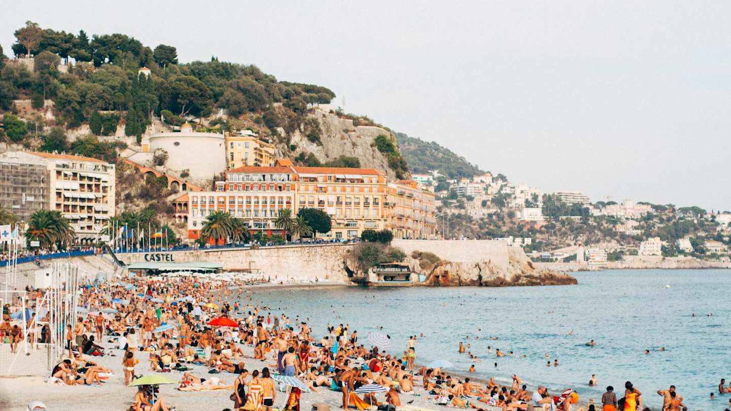 Crowds of tourists relaxing on the French Riviera's picturesque beaches on a summer day, Nice, France
