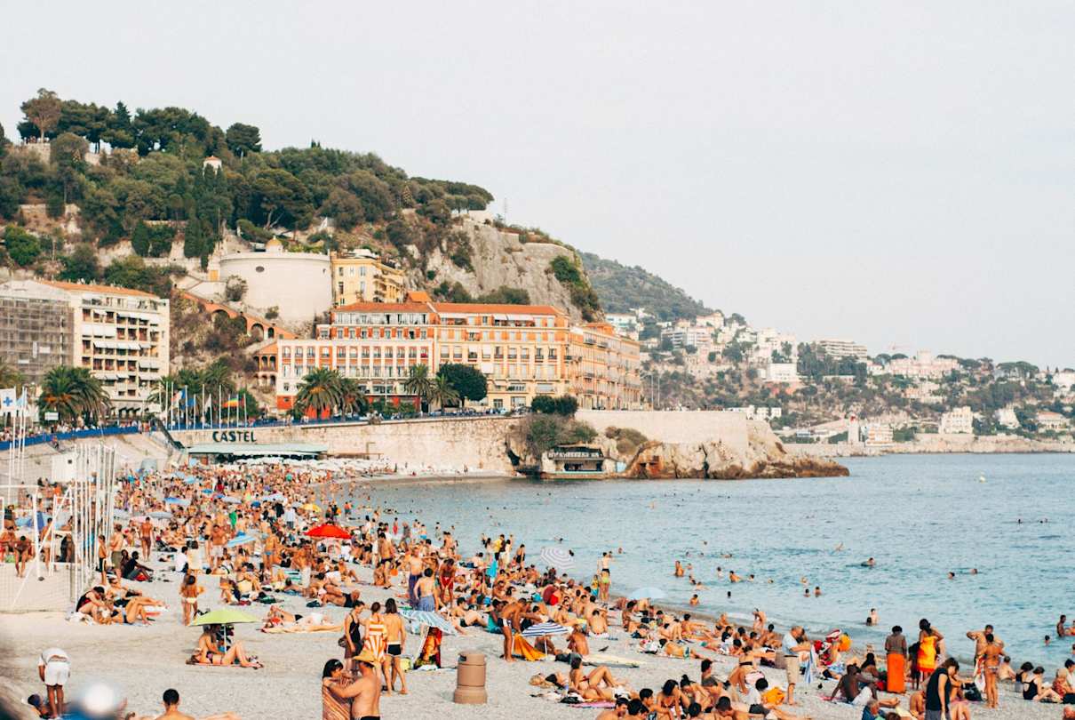 Crowds of tourists relaxing on the French Riviera's picturesque beaches on a summer day, Nice, France