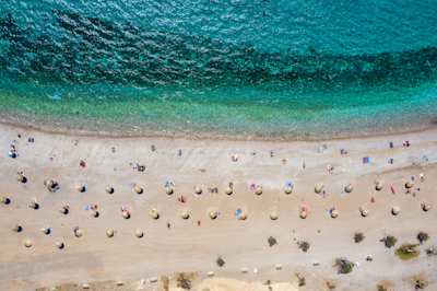 A bird's eye view of the turquoise sea and white sand with parasols at Glyfada Beach, Athens, Greece