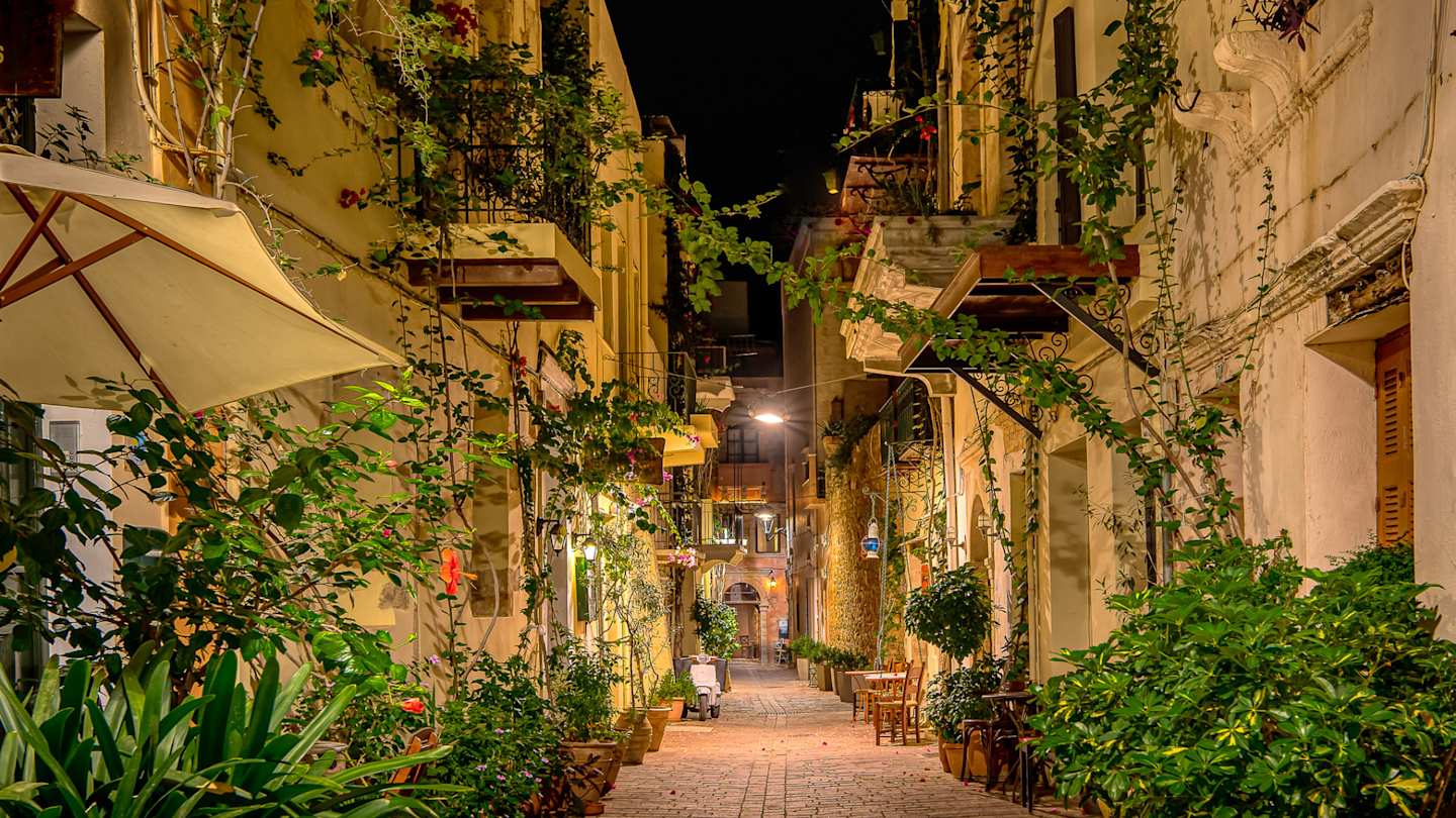 A charming narrow street filled with green plants in the evening in Chania, Crete, Greece