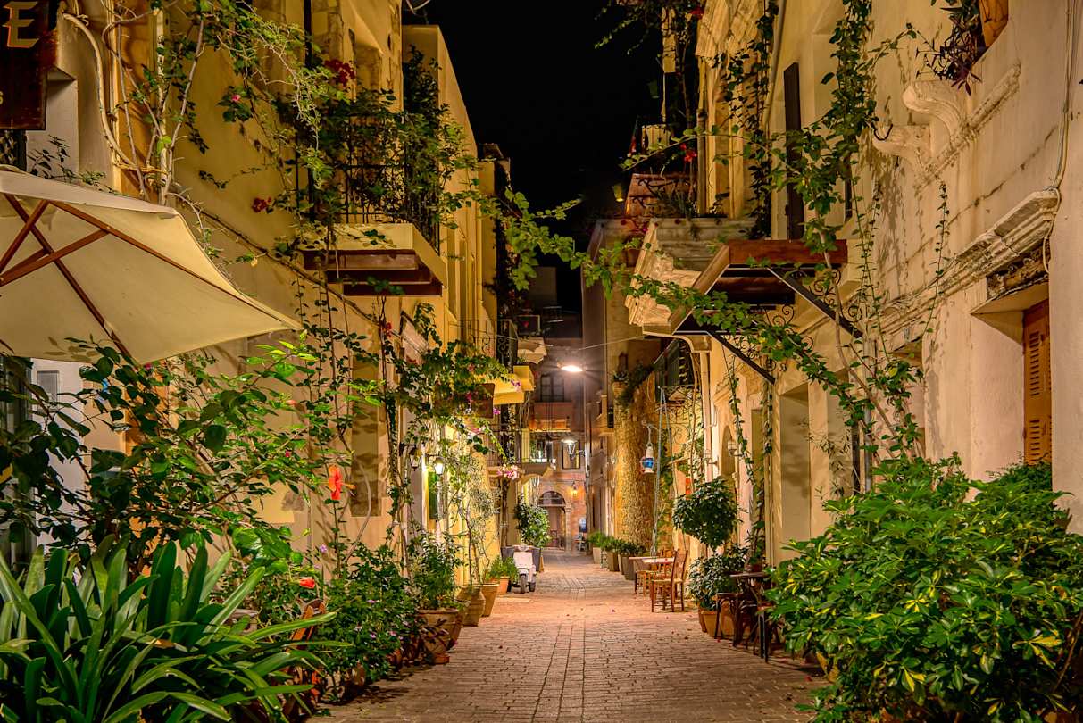 A charming narrow street filled with green plants in the evening in Chania, Crete, Greece