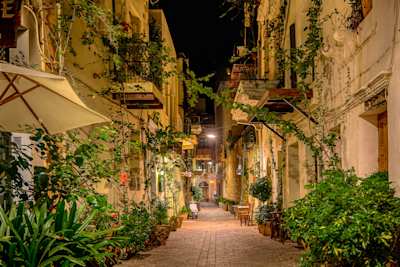 A charming narrow street filled with green plants in the evening in Chania, Crete, Greece