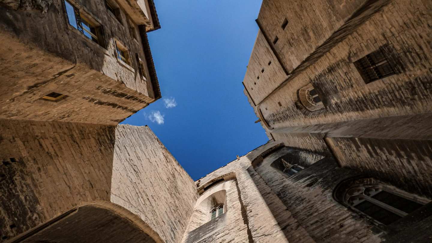 A low-angle view of a tall brown building in Avignon, France on a sunny day
