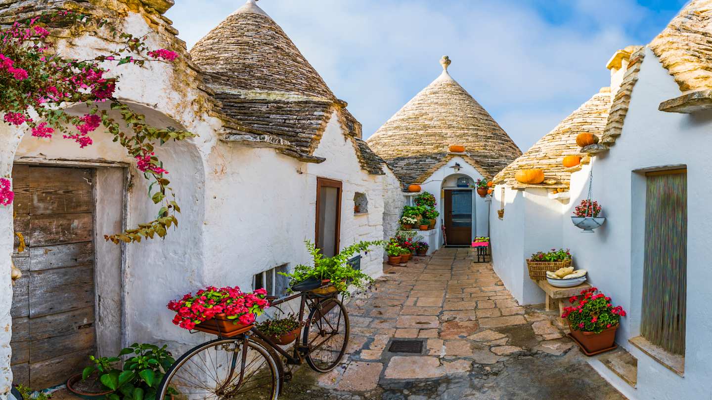 Bicycle with plants on it leaning against traditional trulli houses in Alberobello, Puglia, Italy