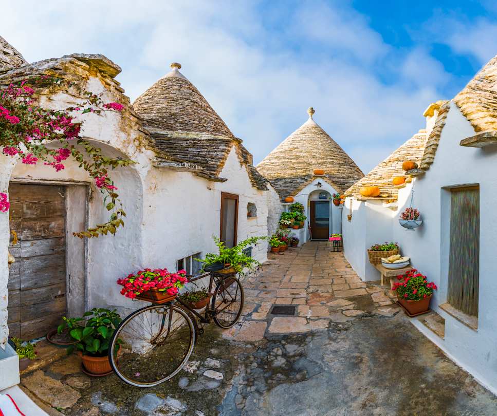 Bicycle with plants on it leaning against traditional trulli houses in Alberobello, Puglia, Italy