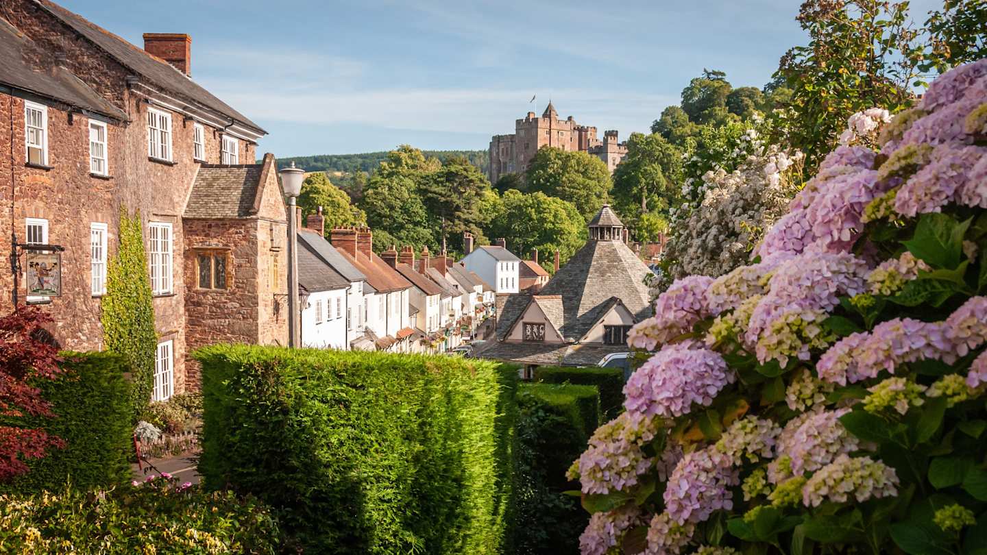 A sunny day in the Exmoor village of Dunster with ancient buildings and blooming flowers, Somerset, England