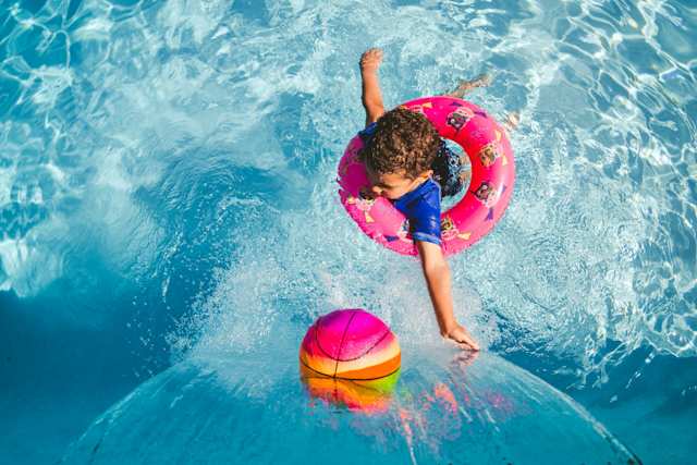 A bird's eye view of a small child playing with a ball in a swimming pool at a waterpark