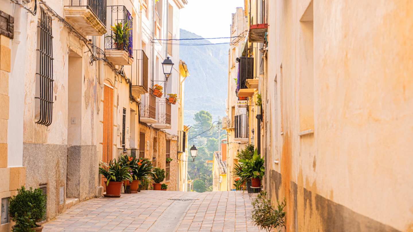 Cobbled street adorned with plants with mountains in the distance, Alicante